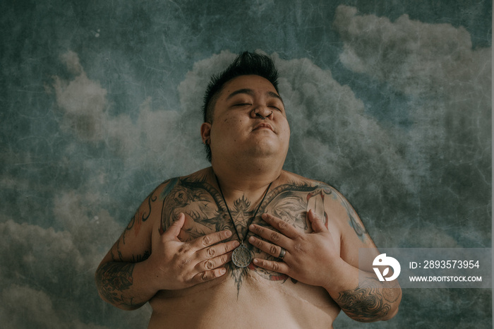 portrait of a plus size asian non-binary trans masculine person looking at camera