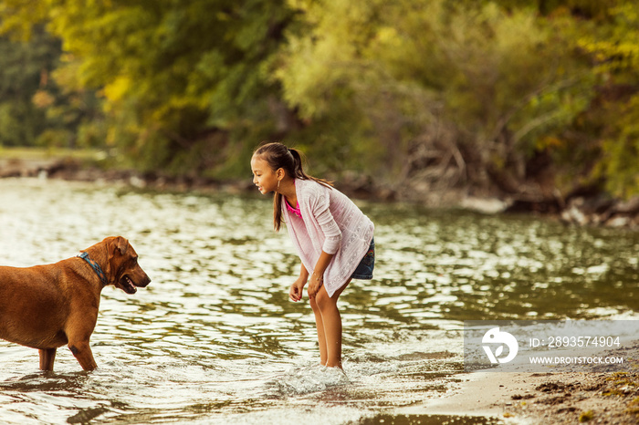 Girl playing with her dog on lakeshore