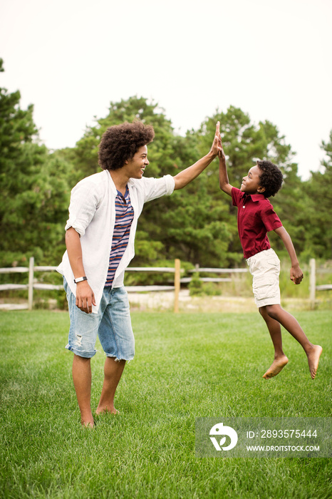 Brothers high-fiving each other in backyard