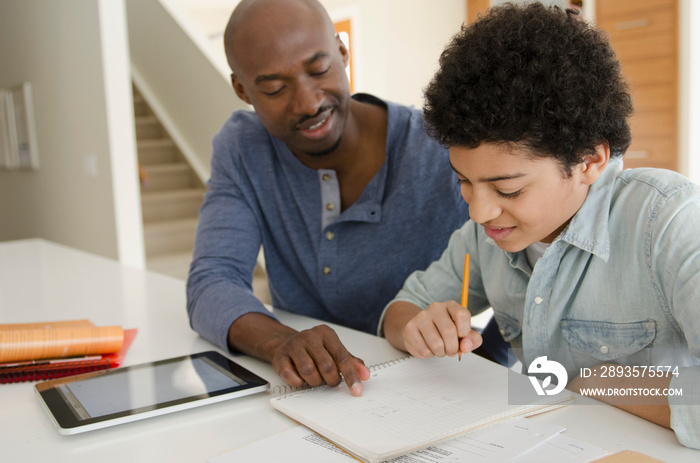 father helping teenage son with homework