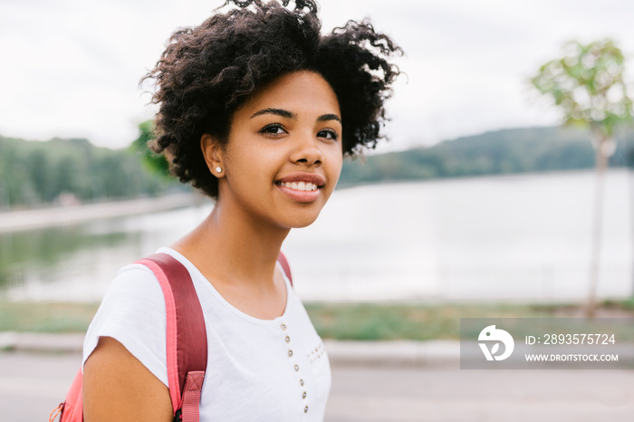 Happy oung african american student female smiling and getting ready to go to college, walking in th