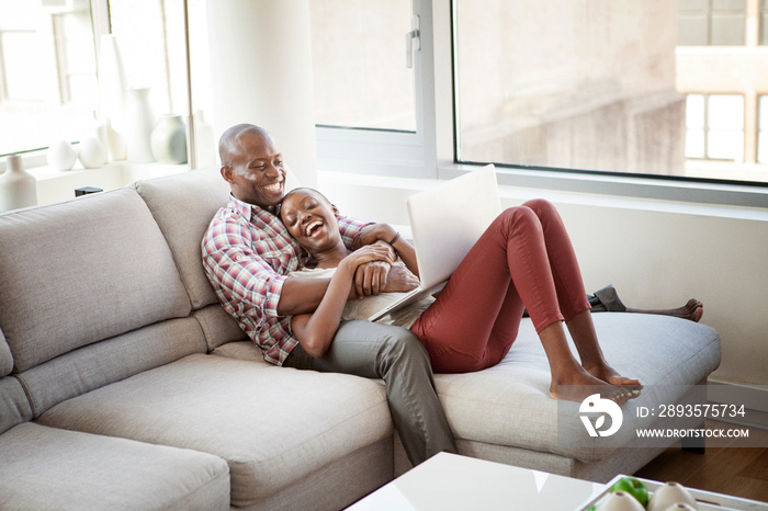 Happy couple at home relaxing using laptop together