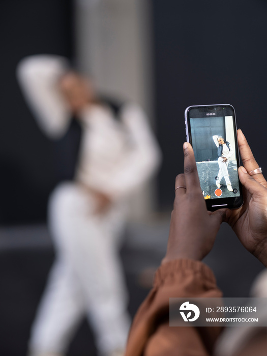 Close-up?of woman photographing friend dancing in city