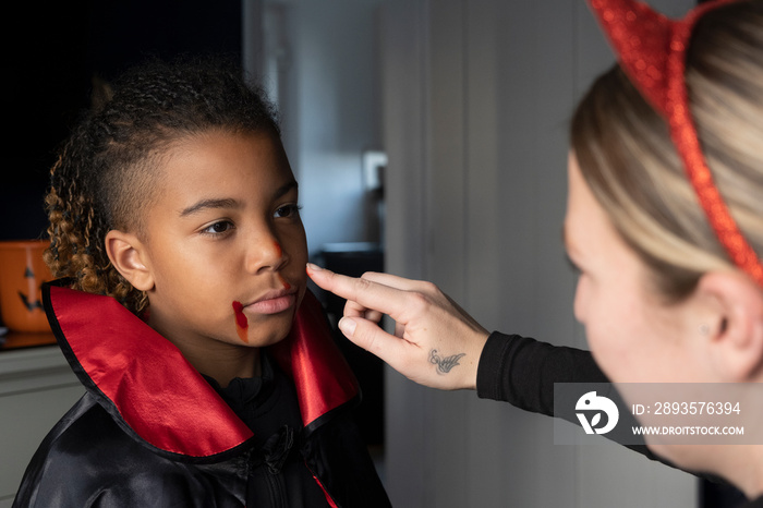 Close-up�of woman applying artificial blood in sons face for Halloween