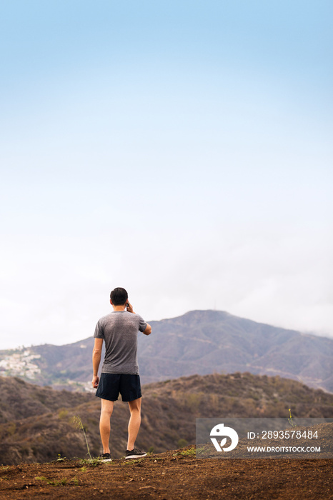 Man talking on phone standing in front of hills