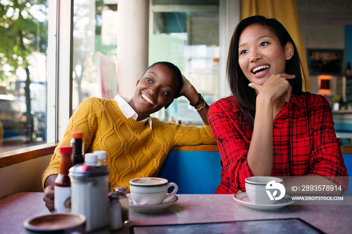 Friends smiling while sitting in cafe