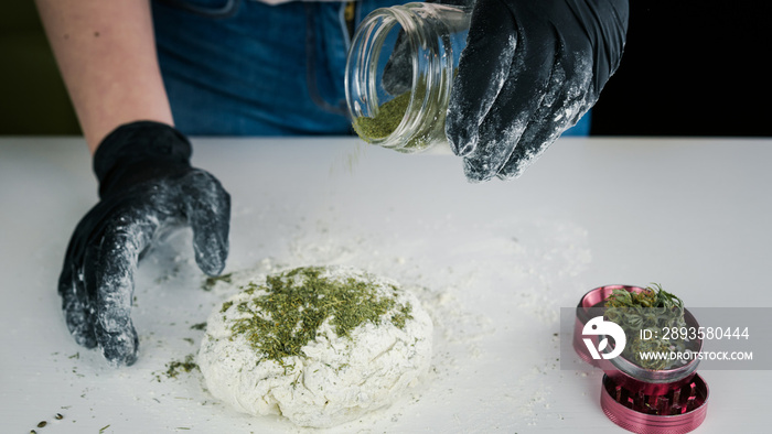 The young female chef preparing to cooking hemp cake or bread. Close-up of fresh dough with cannabis