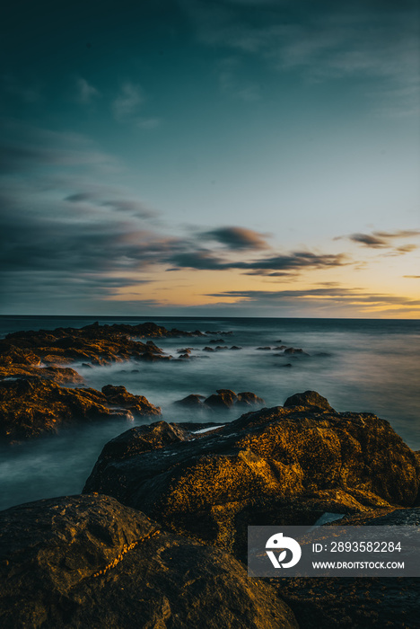 Atardecer en el mar con rocas y acantilados