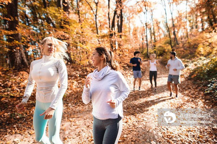 Small group of happy friends running in the woods in the autumn.