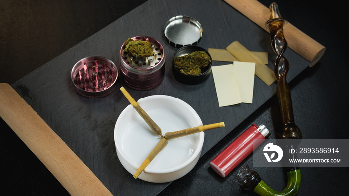 Marijuana joints lie in the ashtray. Smoking pipe, grinder, cannabis.