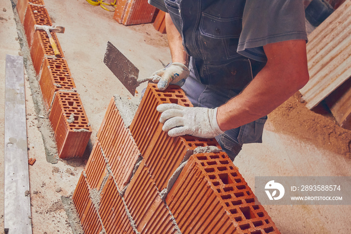 Real construction worker bricklaying the wall indoors.