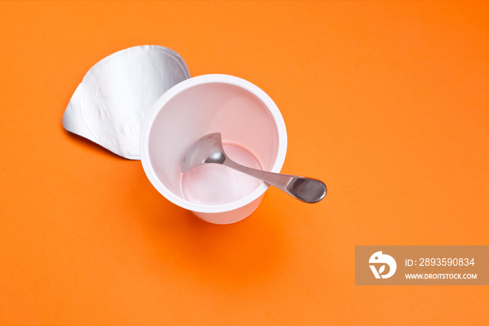 用勺子在橙色背景上清空干净的酸奶杯