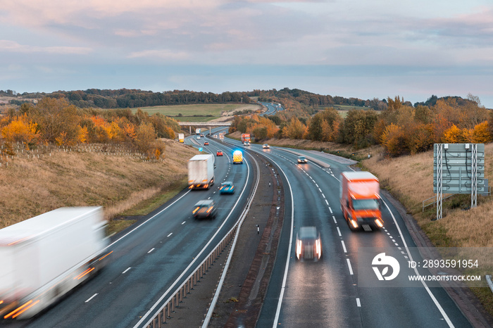 Traffic on the motorway at dusk with cars, trucks and ambulance on the road - Busy rush hour scene i