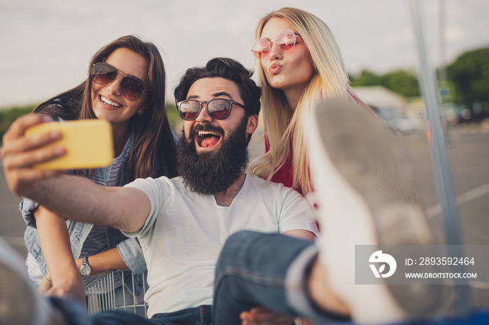 Bearded man taking selfie with women during shopping