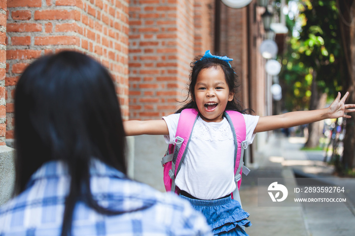 Back to school. Cute asian pupil girl is running to hug her mother after back from school