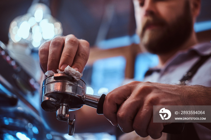 Low angle photo of a barista cleans the portafilter before preparing the cappuccino in a coffee shop