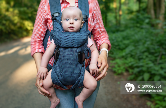 Young mother and her baby girl in a baby carrier.