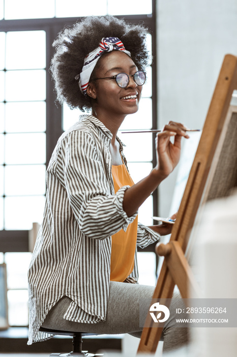 Talented artist sitting in front of drawing easel and painting