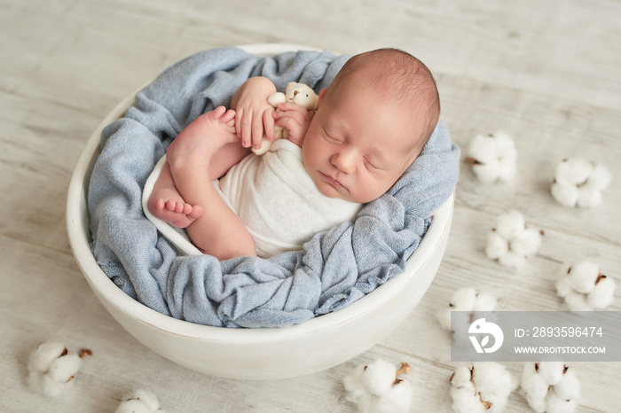可爱的新生小男孩抱着玩具睡在婴儿床上。婴儿用品包装模板。特写肖像