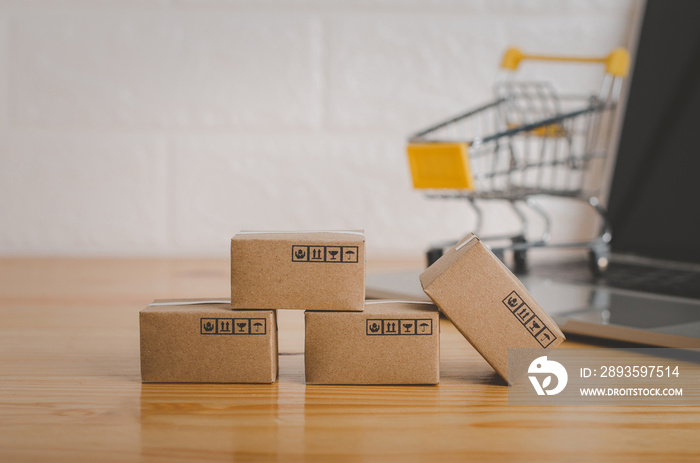 Brown paper boxs with laptop on wood table in office background.Easy shopping with finger tips for c