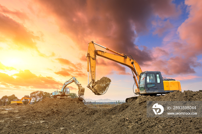 Three excavators work on construction site at sunset