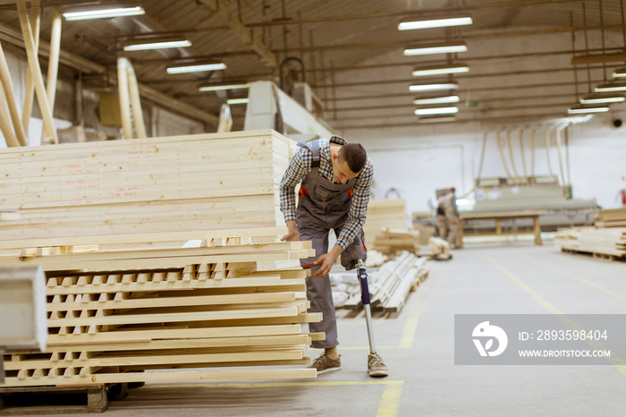 Disabled young man with an artificial leg is working at the furniture  factory