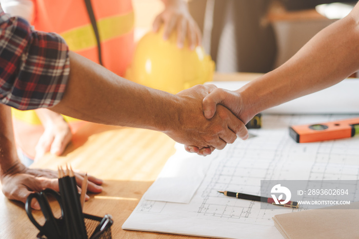 Successful deal, male architect shaking hands with client in construction site after confirm bluepri