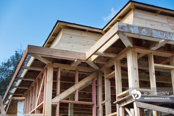 Installation of wooden beams at construction the roof truss system and frame of the house.