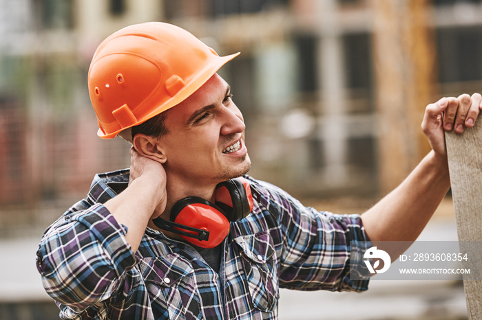 Be careful. Construction worker in protective helmet feeling neck pain while working at construction