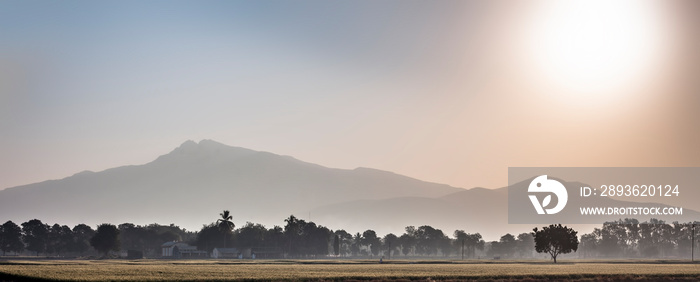 Wide landscape shot of sunrise through mountains in the early morning through fields with mist and f