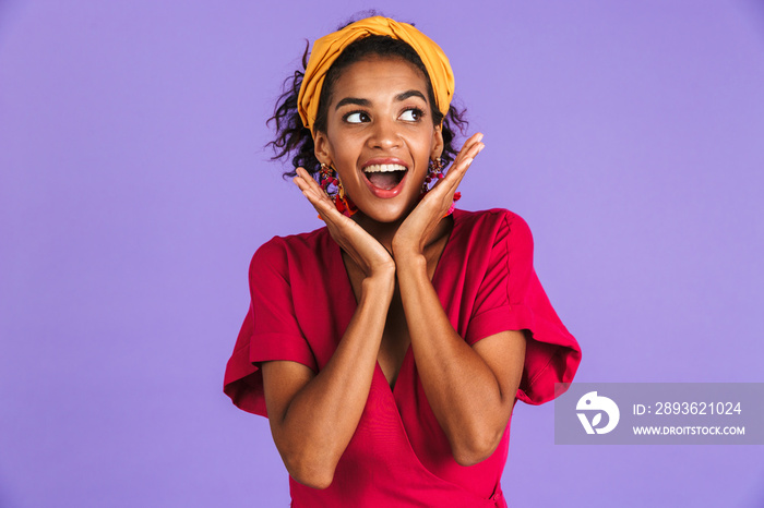 Image of excited american woman 20s in hair band and earrings looking aside with hands near face, is