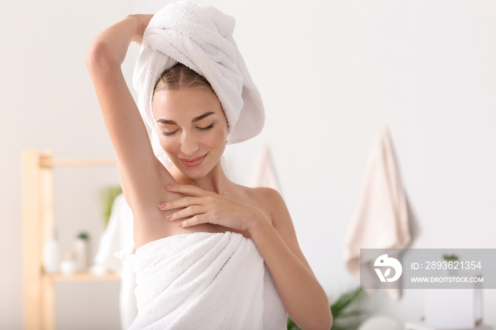 Beautiful young woman with deodorant in bathroom