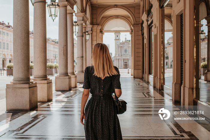 A beautiful woman with blond hair walks through the streets of the city. Girl enjoy holidays in Euro