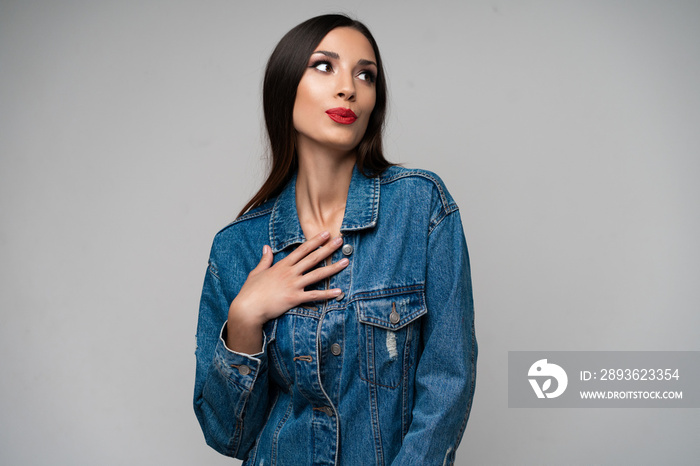 Beautiful caucasian girl in a denim jacket posing in the studio on a white background.