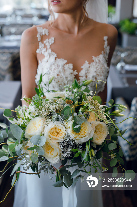 Bride in luxury white wedding dress with the lace holding beautiful rustic wedding bouquet with rose