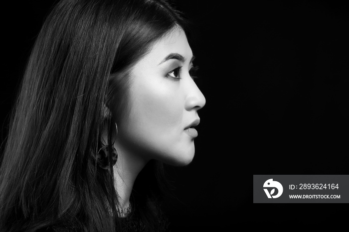 Black and white portrait of young Asian woman on dark background