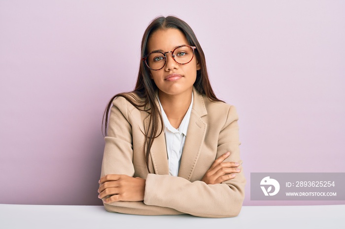 Beautiful hispanic woman working at the office relaxed with serious expression on face. simple and n