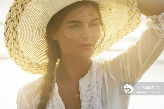 Portrait of beautiful young woman with broad-brimmed hat on the beach