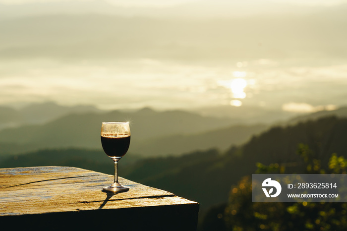红葡萄酒杯，日出俯瞰群山背景。