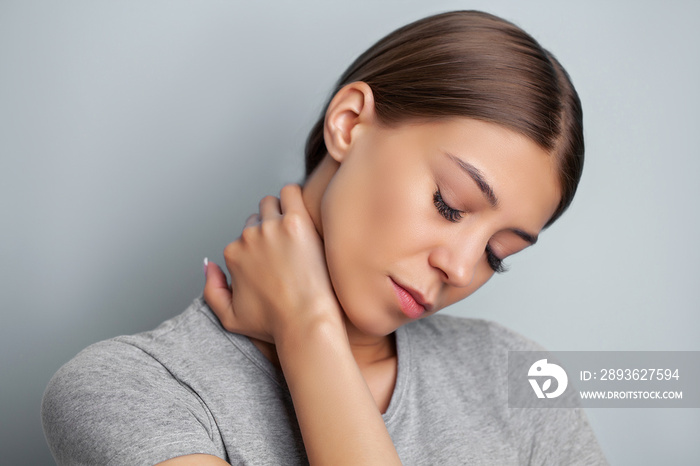 Young woman experiencing severe neck pain while holding her hands