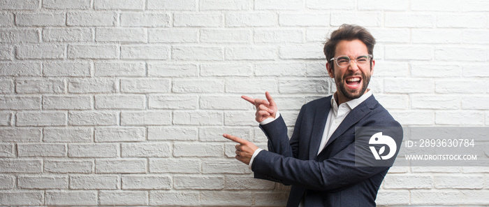 Young friendly business man pointing to the side, smiling surprised presenting something, natural an