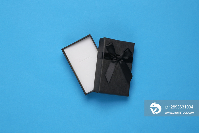 Empty open black gift box on blue background