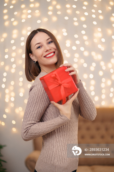 Portrait of young happy woman red lips posing with a wrapped gift box. Close up satisfied woman rece