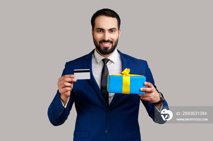 微笑的正面胡子男子的肖像，展示信用卡和礼盒，惊讶地看着，b