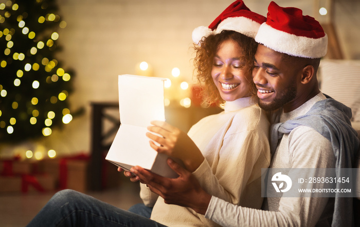 Xmas magic. Cute couple opening Christmas gift box