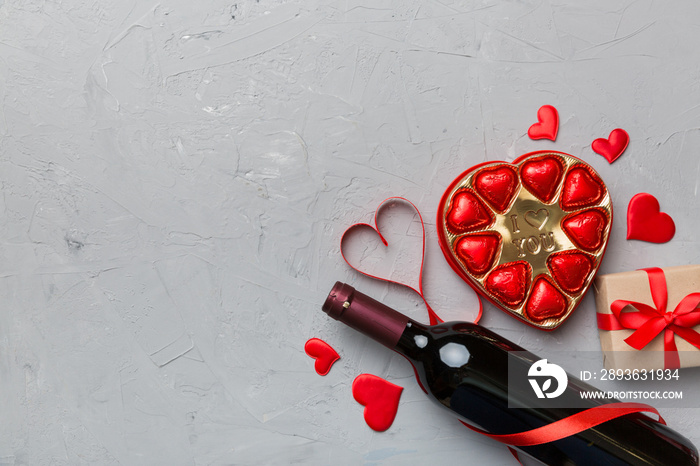 Bottle of red wine on colored background for Valentine Day with gift and chocolate. Heart shaped wit