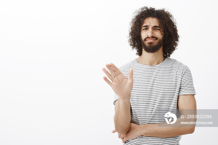 No thanks, I pass. Displeased uninterested handsome curly-haired male in stylish striped t-shirt, wa