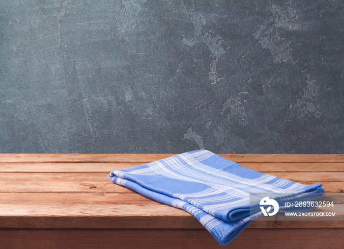 Empty wooden deck table with blue cheched tablecloth over blackboard background for product montage 