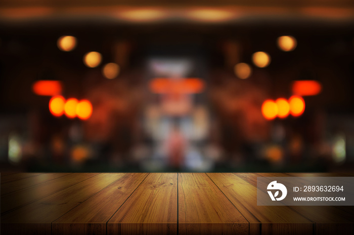 Empty wooden table top with blurred coffee shop or restaurant interior background.