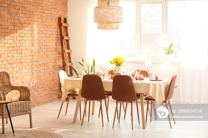 Interior of light room with table set for Easter celebration near window